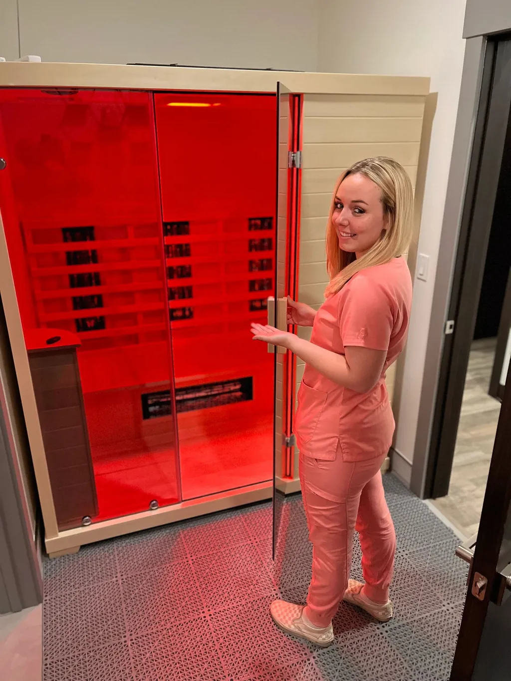 Team member at the red-lit infrared sauna